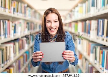Trendy young woman looking happy holding a grey card. Over library background