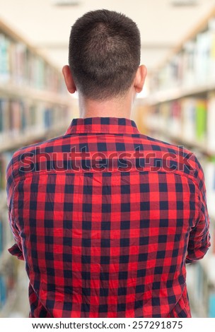 Man with red squares shirt. He is showing his back. Over library background