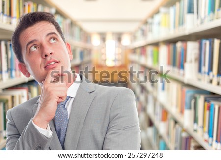 Business man with grey suit. He is looking confident. Over library background