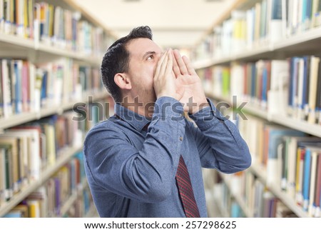 Man wearing a blue shirt and red tie. He is screaming. Over library background