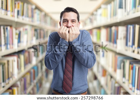 Man wearing a blue shirt and red tie. He is looking scared. Over library background