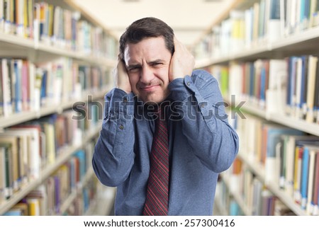 Man wearing a blue shirt and red tie. He is upset because of the noise. Over library background