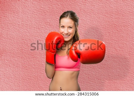 Young woman wearing gym clothes. She has boxing gloves. Over red background