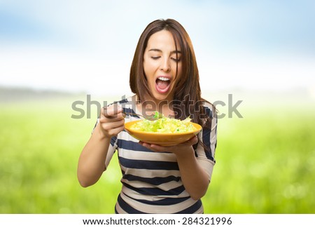 Funny woman eating a salad. Over nature bokeh background