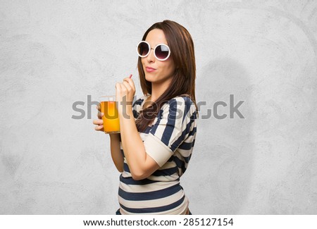 Woman with white sunglasses drinking a juice. Over concrete background