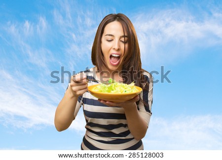 Funny woman eating a salad. Over clouds background