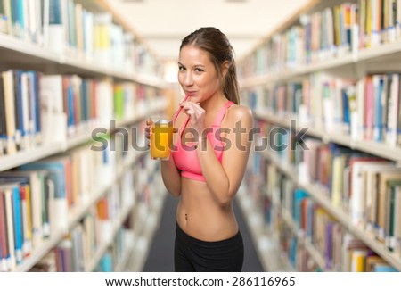 Happy woman drinking a orange juice. Over library background