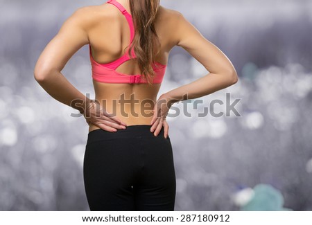 Young woman wearing a gym clothes. She has a back ache