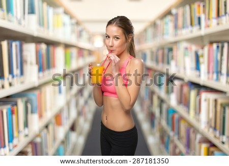 Fit woman drinking a orange juice. Over library background