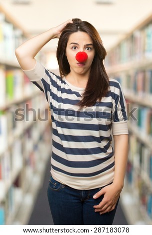 Confused woman with clown nose. Over library background