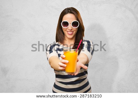 Woman with white sunglasses offering a juice. Over concrete background