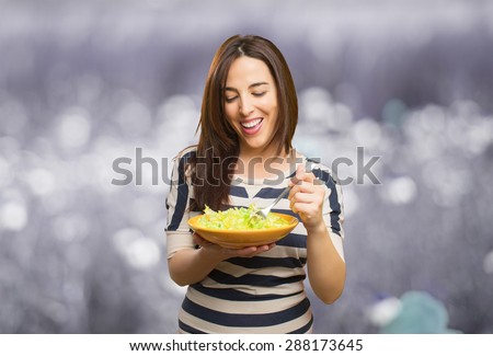 Smiling woman eating a salad. Over abstract background