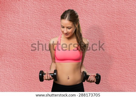 Young woman wearing gym clothes. She is holding dumbbells. Over red background