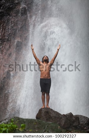Man at waterfall raising his hands in feeling closer to nature