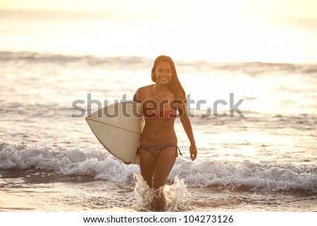 Beautiful asian woman in bikini in the surf with board