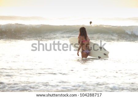 Beautiful asian woman in bikini in the surf with board