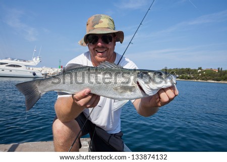 happy fisherman holding a beautiful sea bass