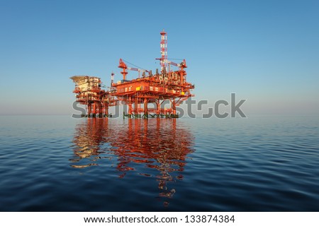 red oil rig platform on calm blue sea