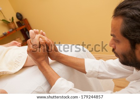 Man giving a foot massage  for a client in relaxing spa environment .