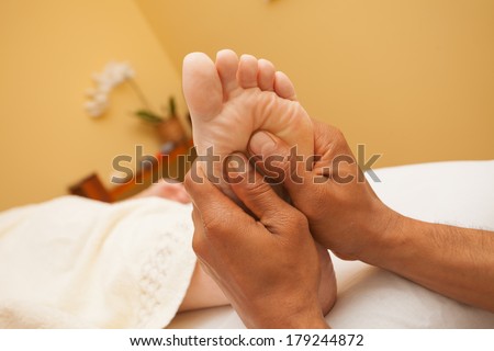Man giving a foot massage  for a client in relaxing spa environment .