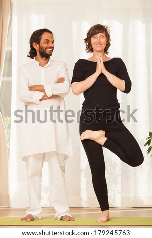 Happy yoga multiethnic couple posing and practicing yoga, in an yoga studio environment full of light.