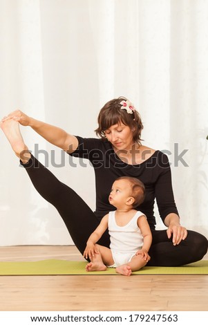 Happy yoga multiethnic mother and child posing and practicing yoga, in an yoga studio environment full of light.
