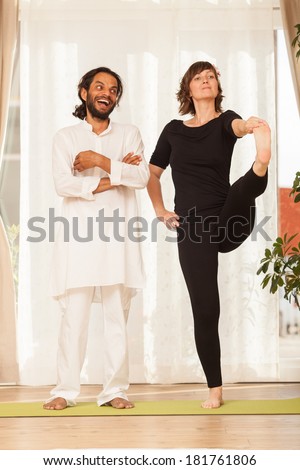 Happy yoga multiethnic couple posing and practicing yoga, in an yoga studio environment full of light.