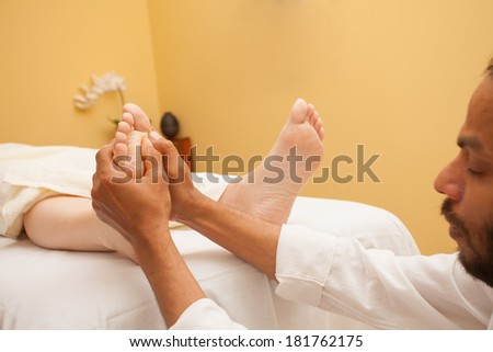 Man giving a foot massage for a client in relaxing spa environment .