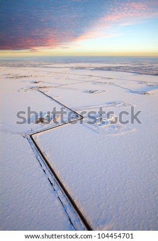 Aerial view of the frozen lake on which are made petroleum production. Roads were run directly through the lake. High clouds bright are lighted by morning sun.