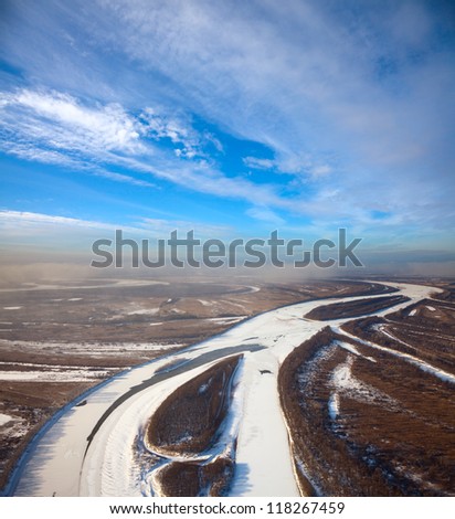 Aerial view of forest of plain and small river during a winter day.