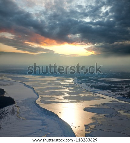 Aerial view of the great river with floating ice floes during sundown. Drifting of ice. Driving of ice. Ice floe.