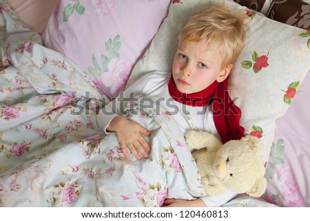 Sick boy is laying in bed with his teddy bear. Them temperature are measured thermometer.