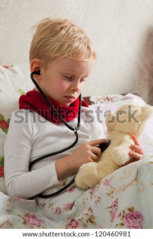 Sick boy is doing examination health for teddy bear with a stethoscope.