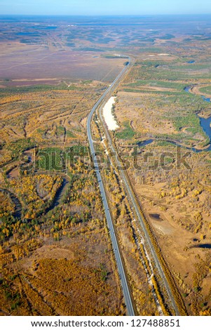 It\'s aerial view over the railroad and highway which run in forest area.