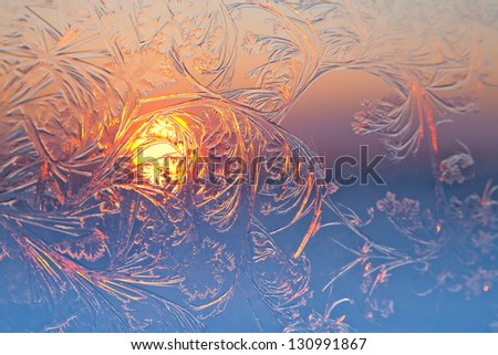 Frosty patterns on the window pane at sunset. Focus are in center.