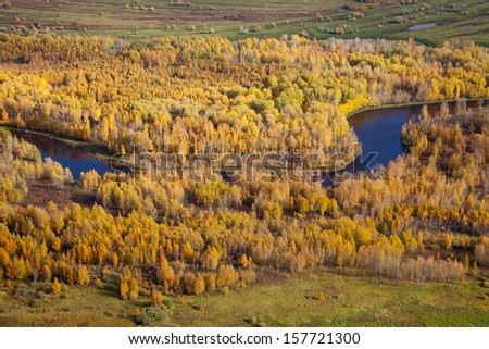 Aerial view of lowland of forest river a autumn during a flight.