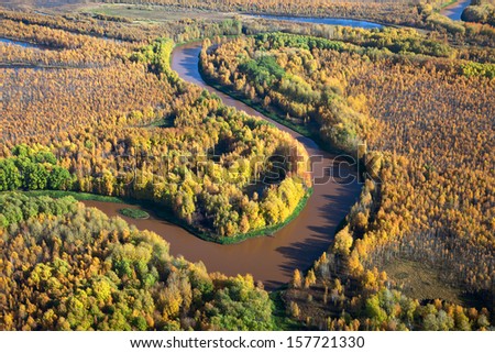 Aerial view of lowland of forest river a autumn during a flight.