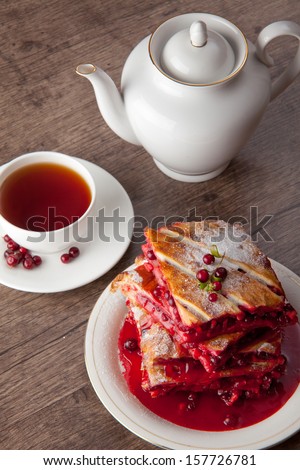 Cranberry Pie for Christmas and tasty tea with foxberry leafs are on wooden table.