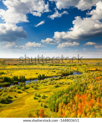 Aerial view of forest river in autumn. Leafs of trees are painted in diferent bright colors.