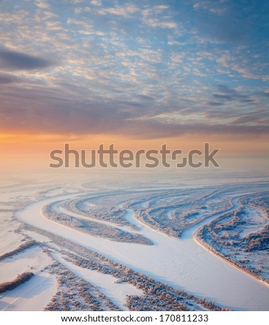 Aerial view of great plain river on the snow-covered plain in time of winter morning.