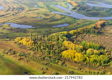 Aerial view of forest river in autumn. Leafs of trees are painted in different bright colors.