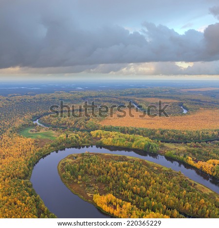 Aerial view of forest river lowland in autumn cloudy day. Leafs of trees are painted in different bright colors.