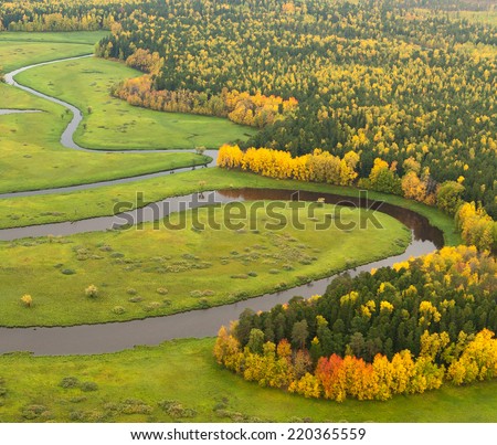 Aerial view of forest river in autumn. Leafs of trees are painted in different bright colors.