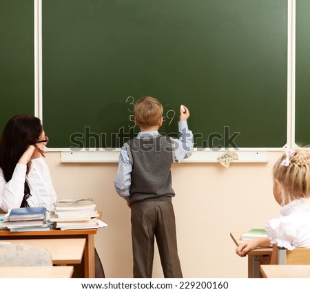 Schoolboy solves example at the school board during a lesson in mathematics.
