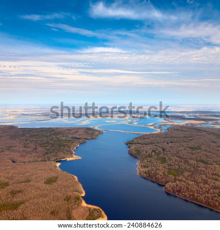 Aerial view over flood-land beside great river during spring. Great plain is divided into many parts by a lot of number of rivers and channels.  The trees in forest don\'t have leaves yet.