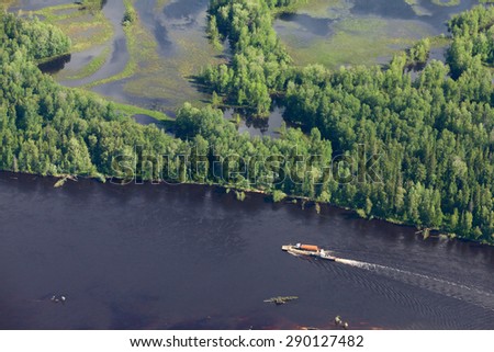Aerial view of forest the river during summer day. The ship with barge moves along the river. The refueler is on the barge.