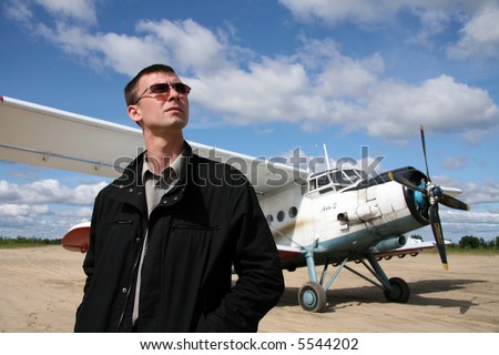 The Young man peers into the sky on background of the white airplane.