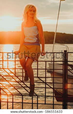 Beautiful blonde watches as the sun sets on the lake