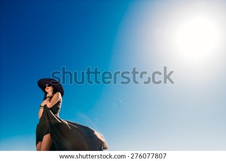 beautiful girl in black long dress on a background of blue sky