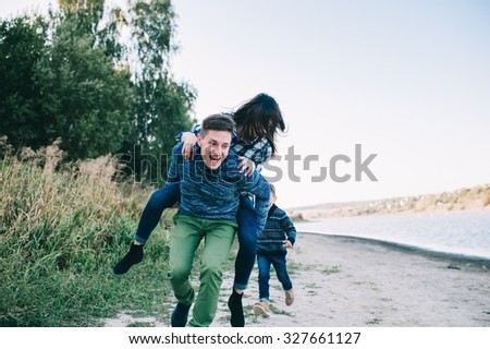 vacation young family near the lake, happy father, mother and son running on beach